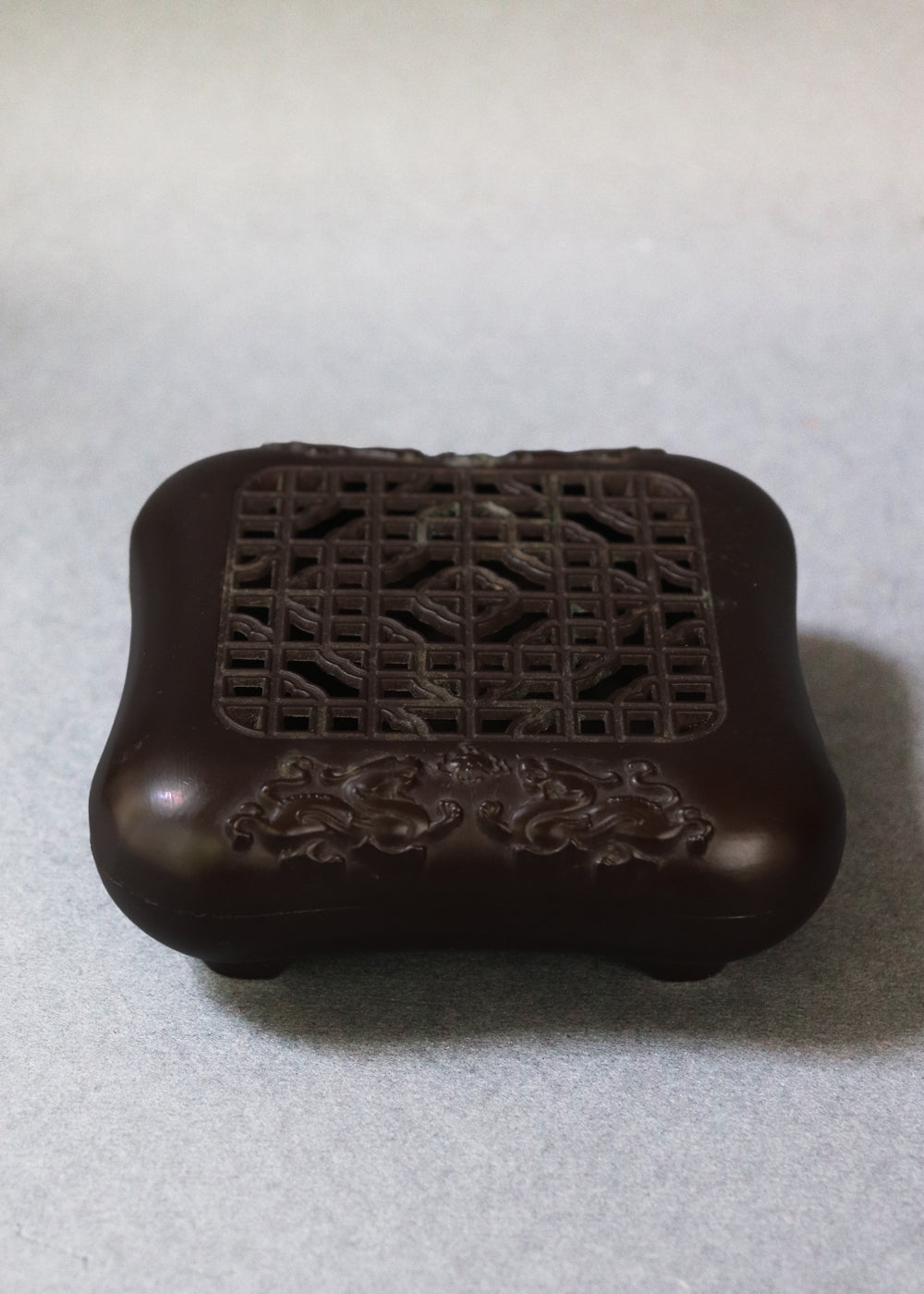Late Qing dynasty bronze censer with a beautiful open lattice work lid. It has double dragon motifs on two sides, symboling good fortune and protection. The lattice allows fragrant smoke to curl up gently through the pattern. The censer has soft rounded edges, and the base has a four-character seal mark that reads "Qianlong Nian Zhi”, or Made during the Qianlong period. This would most likely be an early 1900s piece, made in China.