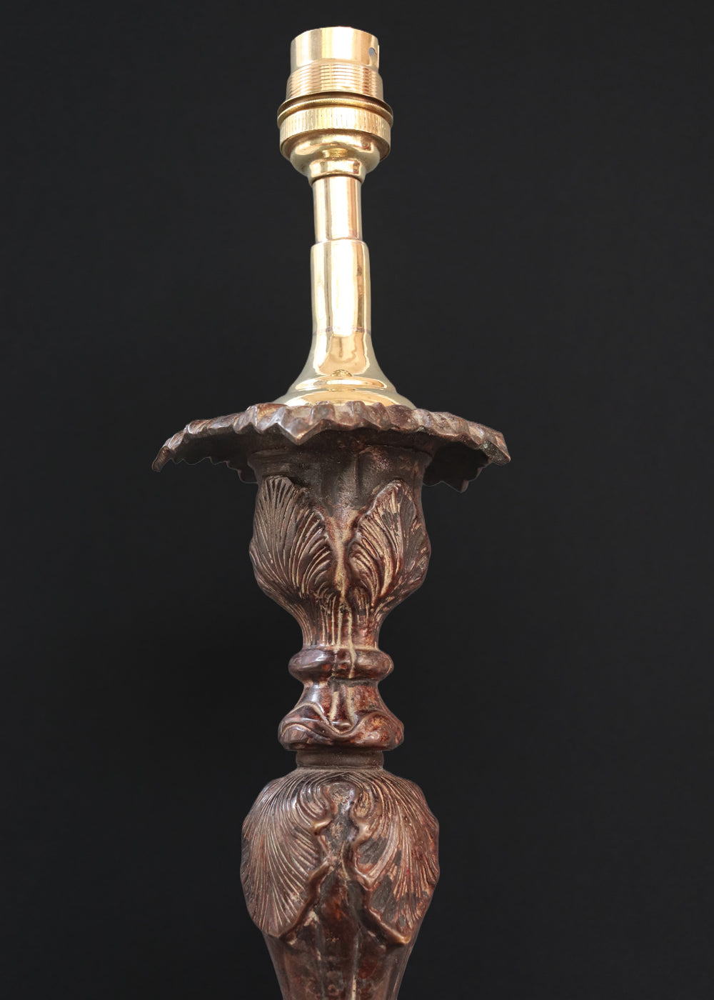 Unusually large bronze candle stick in neoclassical design. The column ends in a beautiful bud shape, and the knop and sconce are all covered in anacthus leaves. The raised round base has an alternating pattern of a spray of leaves and drops.. The sconce opens up into a beautiful flower. The sconce and the base has a conduit for a wire to be passed through so that this candle stand can be converted into a lamp as well. Should be from the mid 1900s, England.