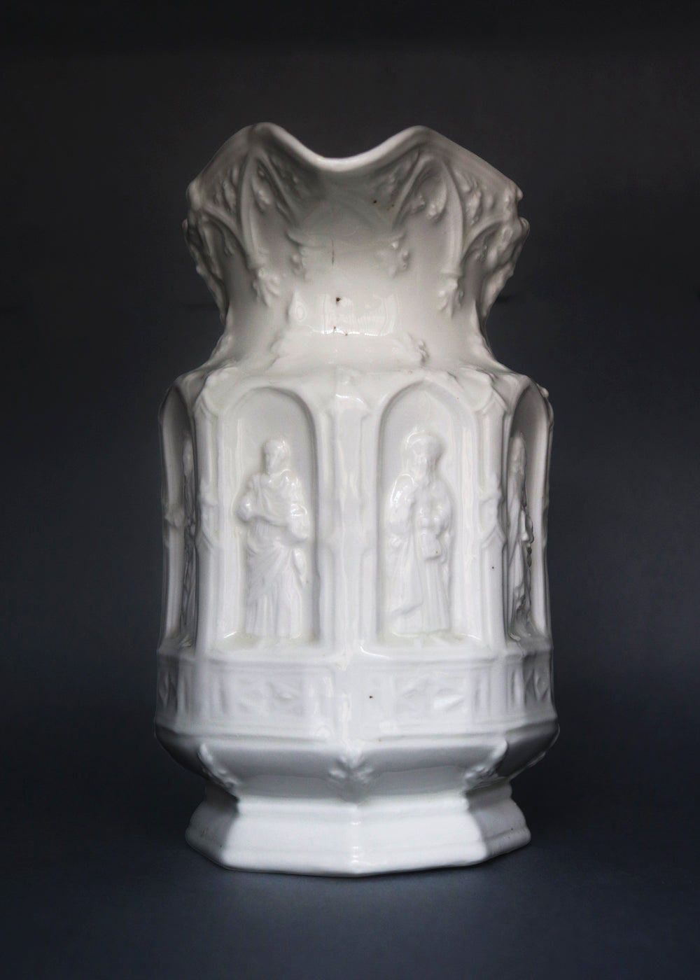Vintage Apostle Jug featuring raised, molded figures of the apostles under Gothic-style architectural arches. This design was first made by Charles Meigh in 1842 in Staffordshire, and these pieces are displayed at the V&A and the Metropolitan Museum. The arcaded "Gothic" decoration is a response by the pottery industry to the ideas of the influential architect and designer Augustus Charles Pugin (1762–1832). The design was so popular that several companies continued making them more than a 100 years aft