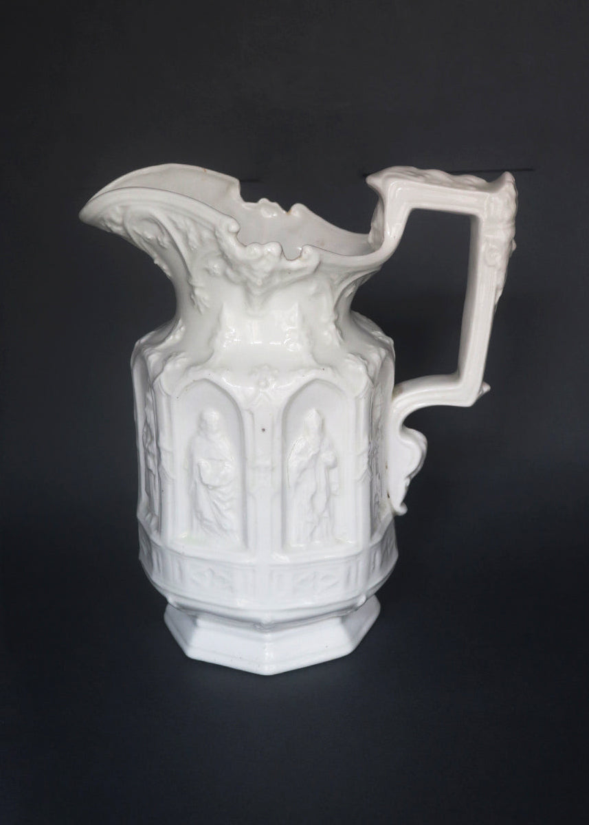 Vintage Apostle Jug featuring raised, molded figures of the apostles under Gothic-style architectural arches. This design was first made by Charles Meigh in 1842 in Staffordshire, and these pieces are displayed at the V&A and the Metropolitan Museum. The arcaded "Gothic" decoration is a response by the pottery industry to the ideas of the influential architect and designer Augustus Charles Pugin (1762–1832). The design was so popular that several companies continued making them more than a 100 years aft
