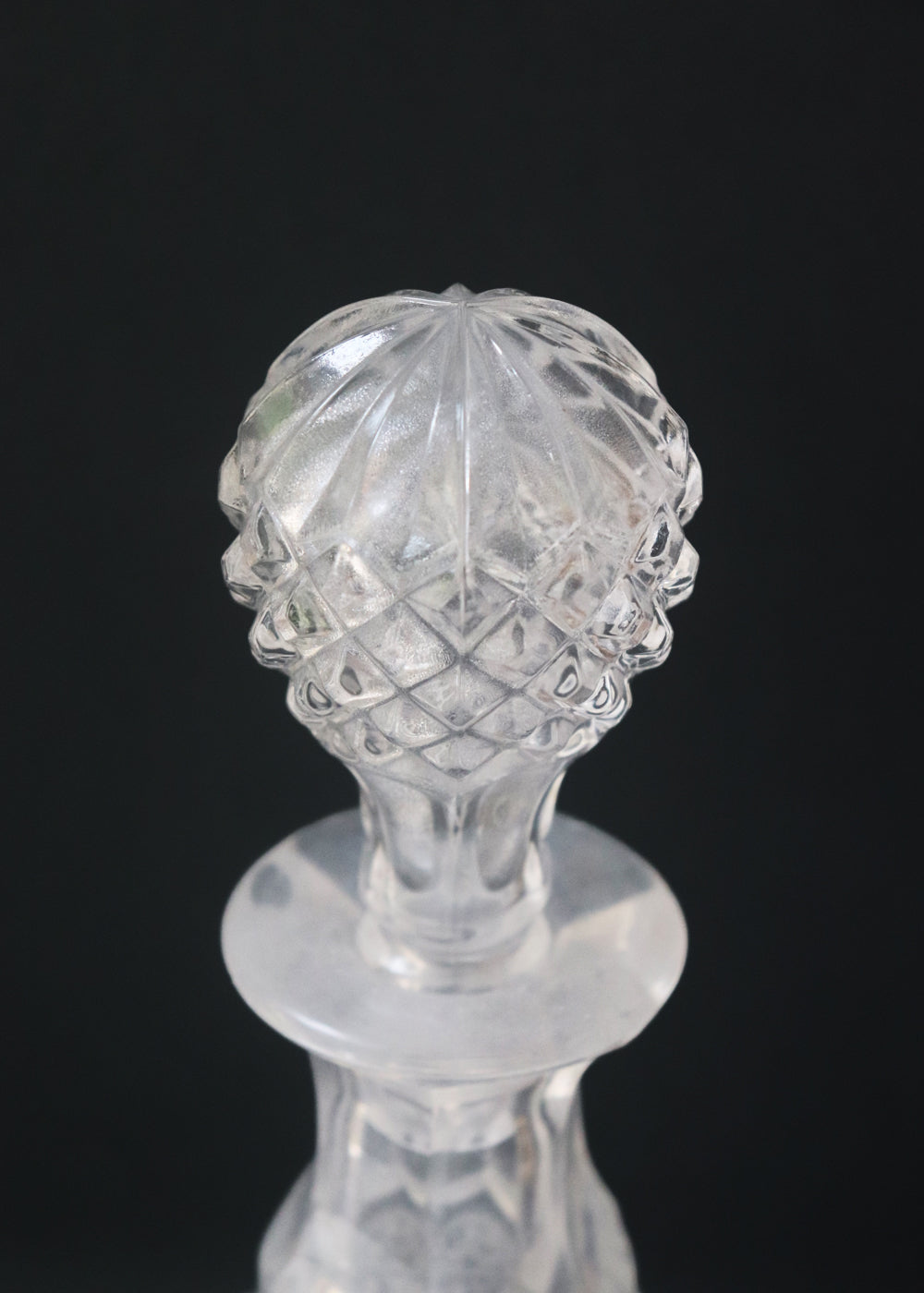 Vintage heavy cut glass decanter most likely meant for port wine. The bell shaped body is deeply facetted with patterns and has etched flowers around it. A diamond patterned ball shaped stopper sits atop the narrow neck. The crystal is somewhat cloudy but otherwise the decanter is in perfect condition. Should be from the mid 1900s, and most likely made in America.