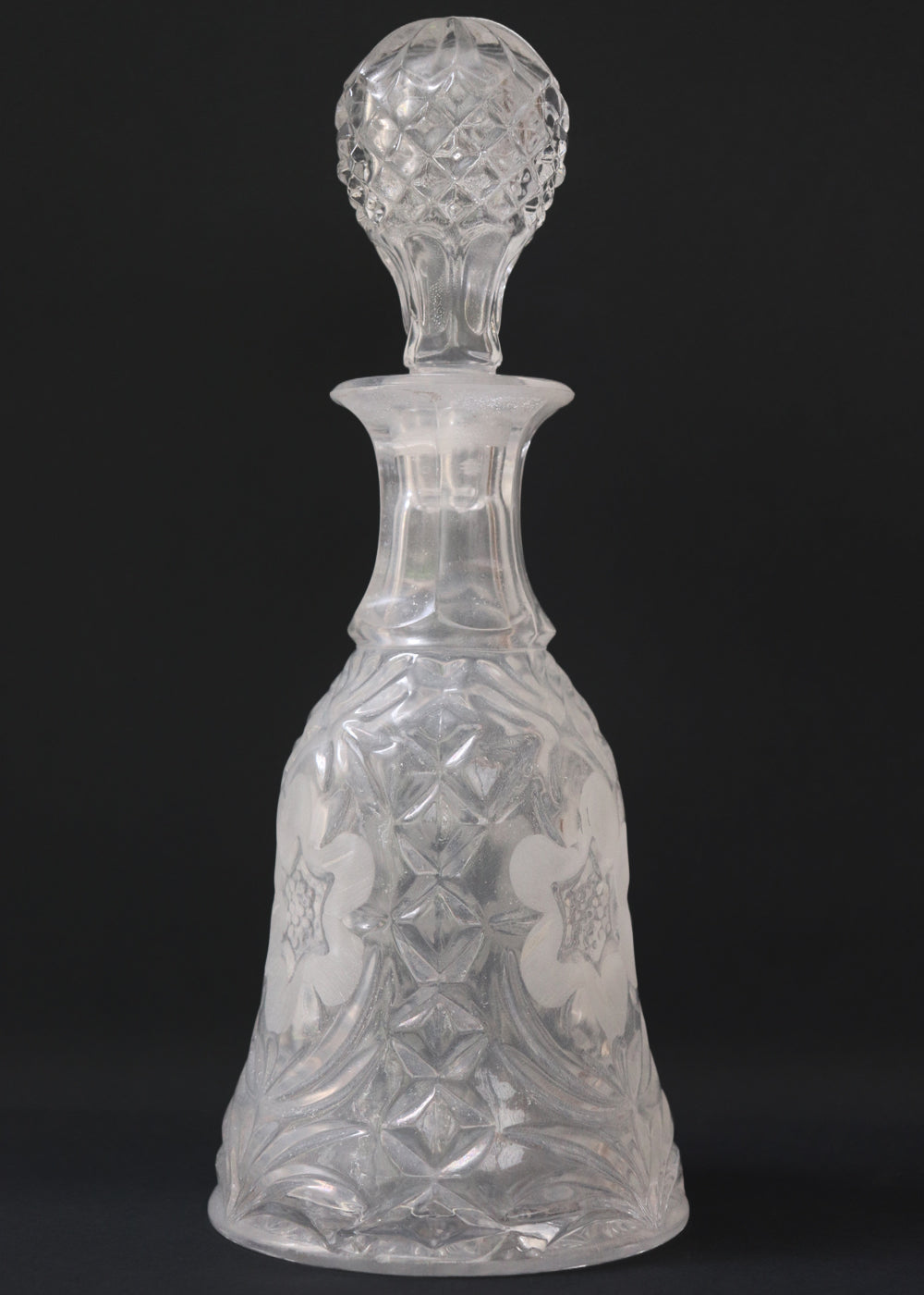 Vintage heavy cut glass decanter most likely meant for port wine. The bell shaped body is deeply facetted with patterns and has etched flowers around it. A diamond patterned ball shaped stopper sits atop the narrow neck. The crystal is somewhat cloudy but otherwise the decanter is in perfect condition. Should be from the mid 1900s, and most likely made in America.