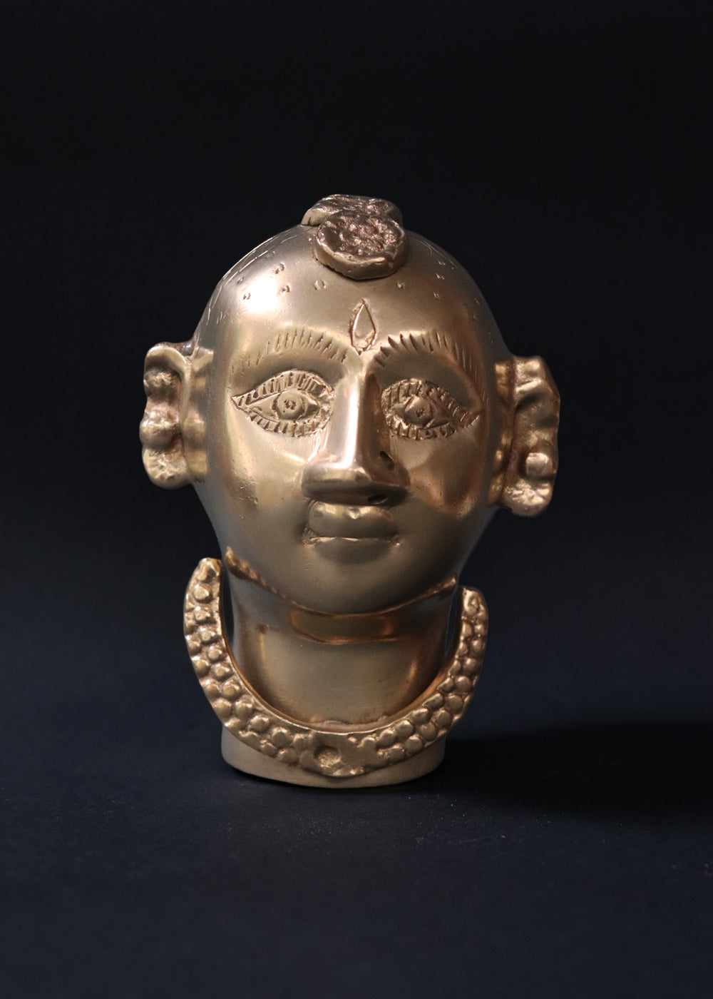 Vintage Brass Gauri head, the divine embodiment of Shakti, the Mother Goddess, the benevolent form of Parvati. She is highly bejewelled with a neckpiece, head and ear ornaments. The nose has a provision to adorn it with a nose ring. The piece has ben recently polished, and is in great condition From the mid 1900s India.