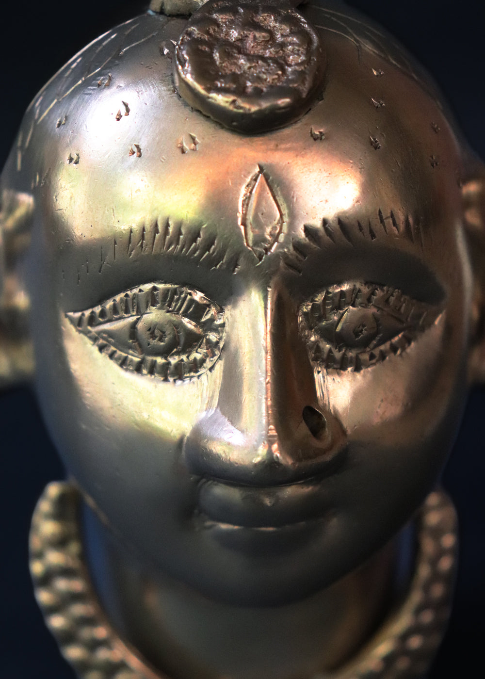 Vintage Brass Gauri head, the divine embodiment of Shakti, the Mother Goddess, the benevolent form of Parvati. She is highly bejewelled with a neckpiece, head and ear ornaments. The nose has a provision to adorn it with a nose ring. The piece has ben recently polished, and is in great condition From the mid 1900s India.