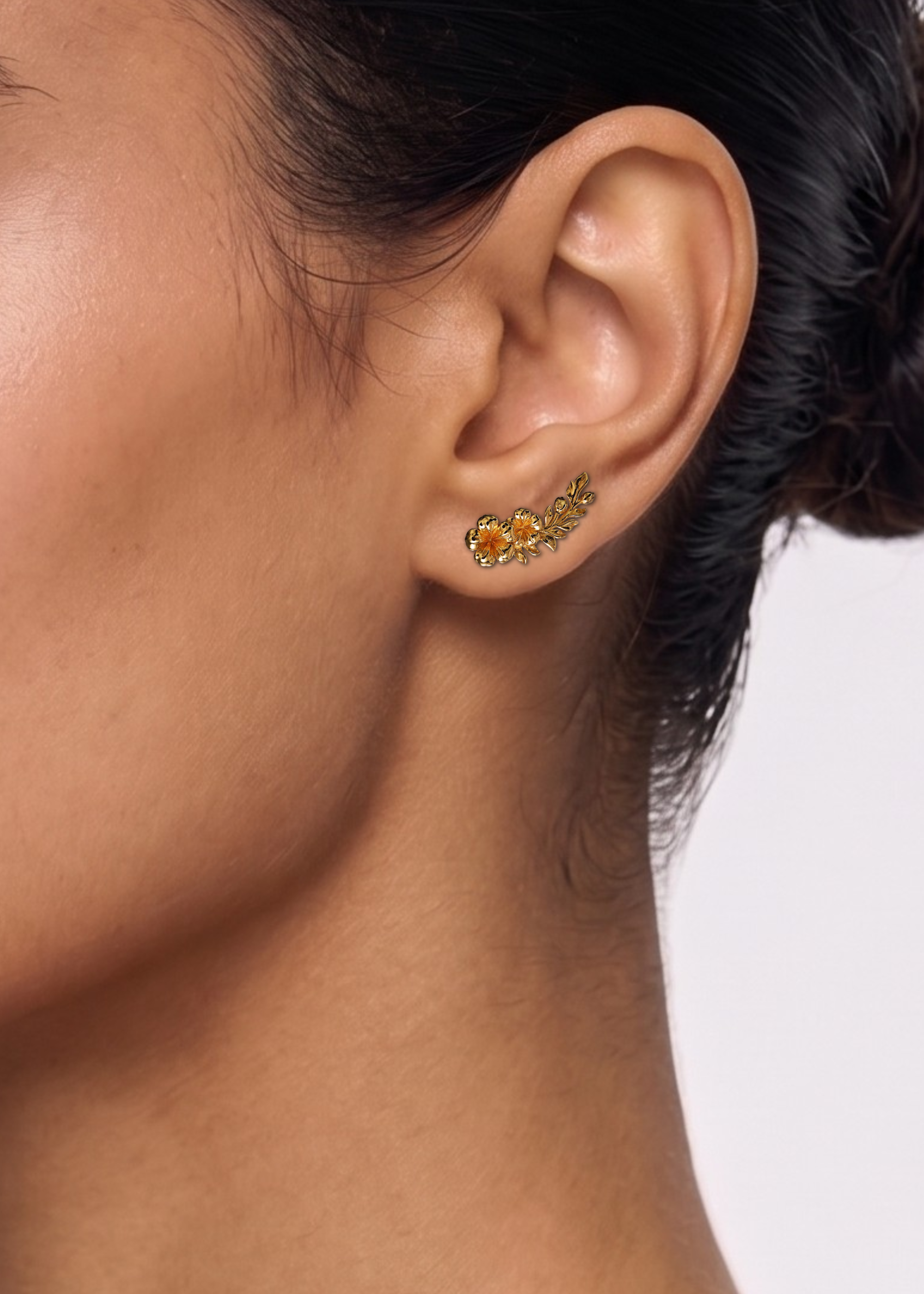 A pair of gold-toned floral stud earrings with leafy sprigs and small flower details