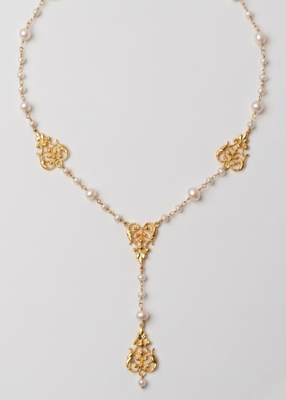 Gold necklace with floral designs on a light gray background