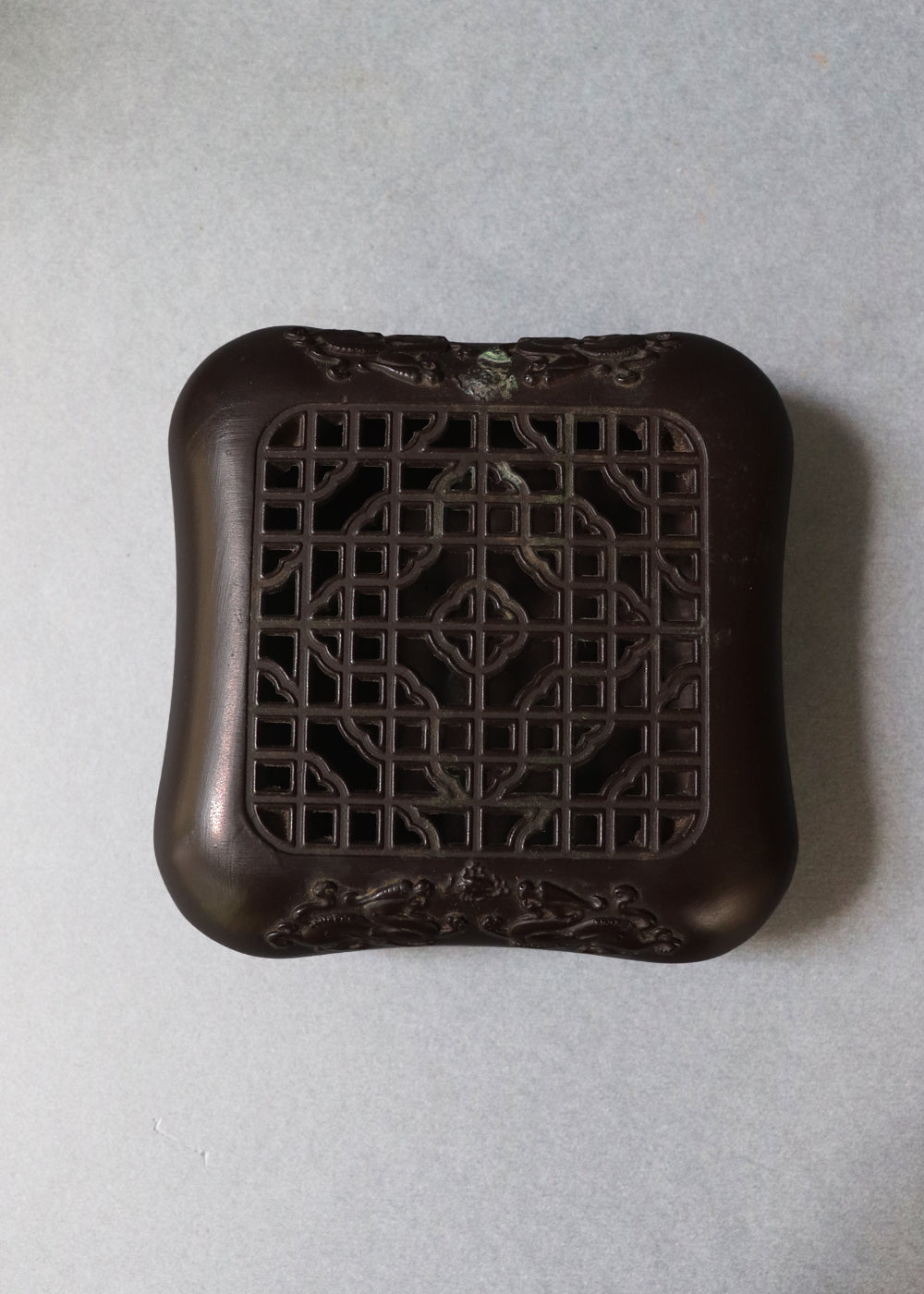 Late Qing dynasty bronze censer with a beautiful open lattice work lid. It has double dragon motifs on two sides, symboling good fortune and protection. The lattice allows fragrant smoke to curl up gently through the pattern. The censer has soft rounded edges, and the base has a four-character seal mark that reads "Qianlong Nian Zhi”, or Made during the Qianlong period. This would most likely be an early 1900s piece, made in China.