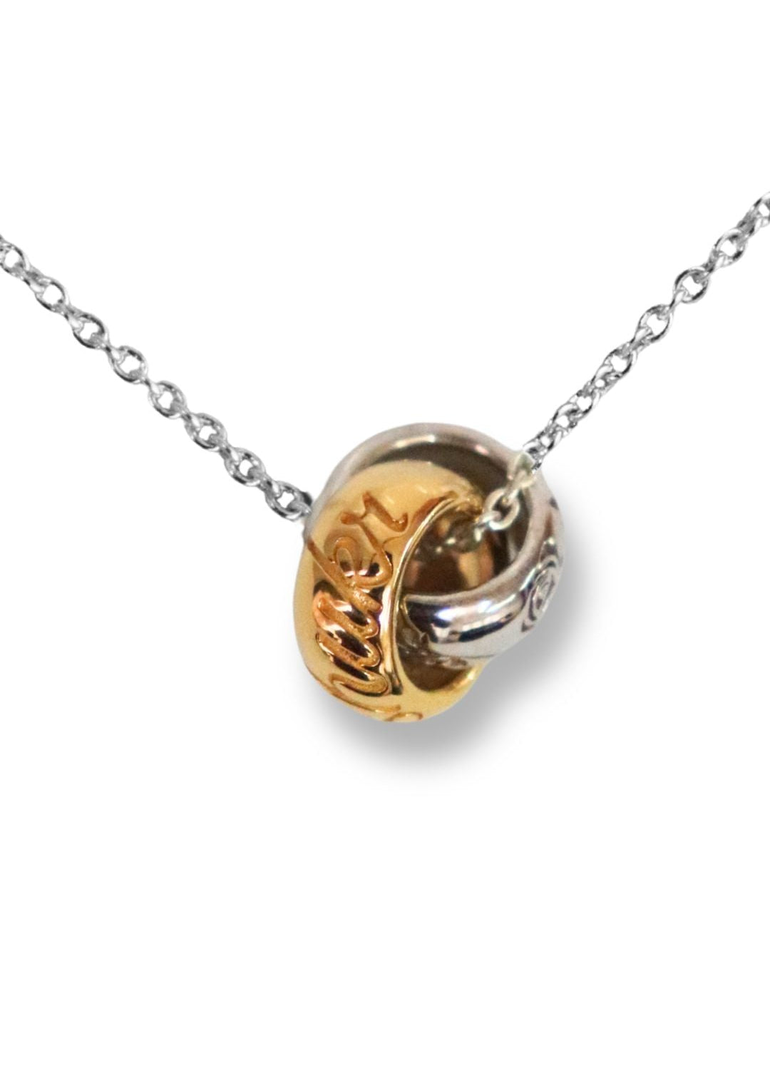 Two-tone gold and silver pendant necklace with an engraved decorative floral motif and words and polished round pendant