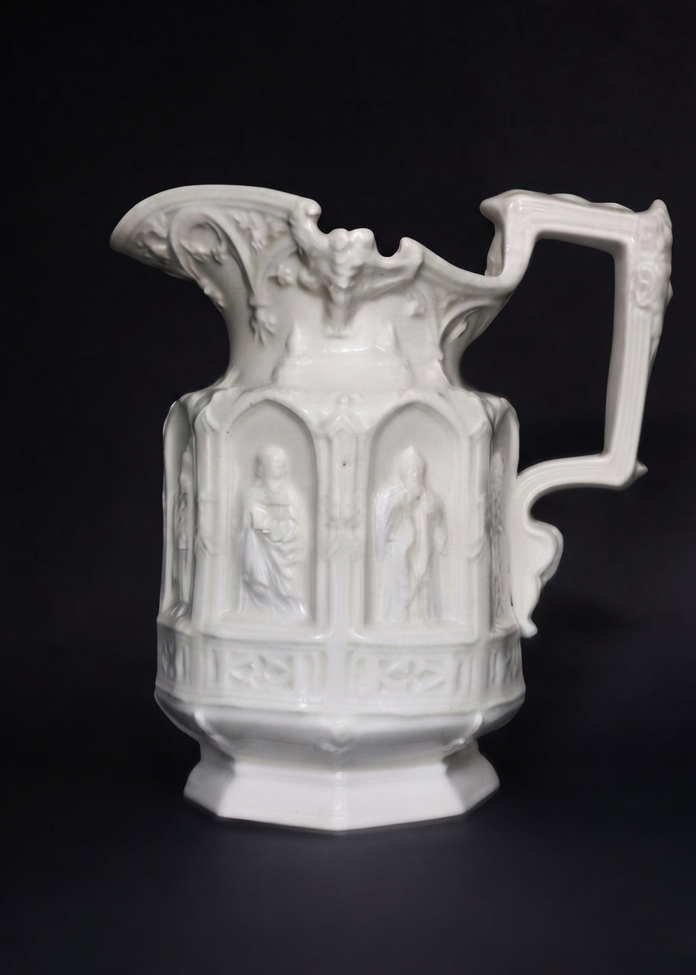 Vintage Apostle Jug featuring raised, molded figures of the apostles under Gothic-style architectural arches. This design was first made by Charles Meigh in 1842 in Staffordshire, and these pieces are displayed at the V&amp;A and the Metropolitan Museum. The arcaded "Gothic" decoration is a response by the pottery industry to the ideas of the influential architect and designer Augustus Charles Pugin (1762–1832). The design was so popular that several companies continued making them more than a 100 years aft
