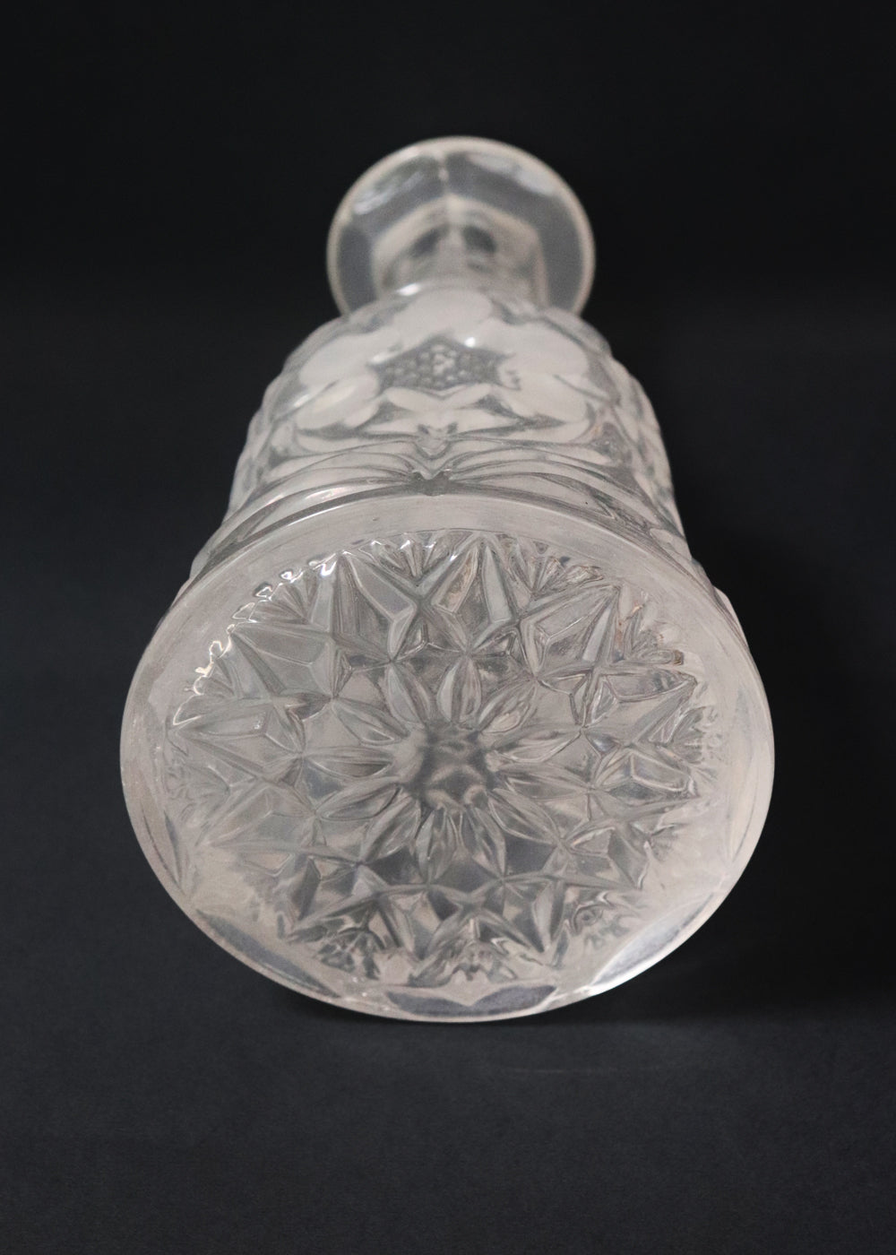 Vintage heavy cut glass decanter most likely meant for port wine. The bell shaped body is deeply facetted with patterns and has etched flowers around it. A diamond patterned ball shaped stopper sits atop the narrow neck. The crystal is somewhat cloudy but otherwise the decanter is in perfect condition. Should be from the mid 1900s, and most likely made in America.