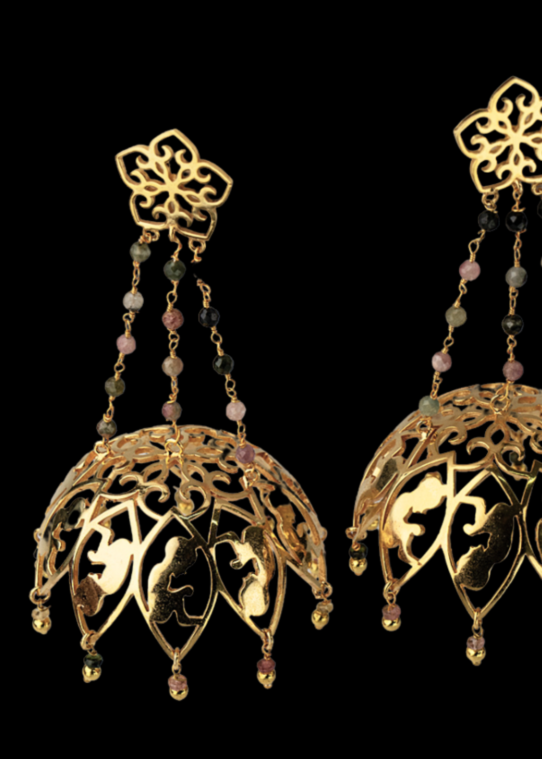 Gold earrings with intricate designs and bead accents on a black background