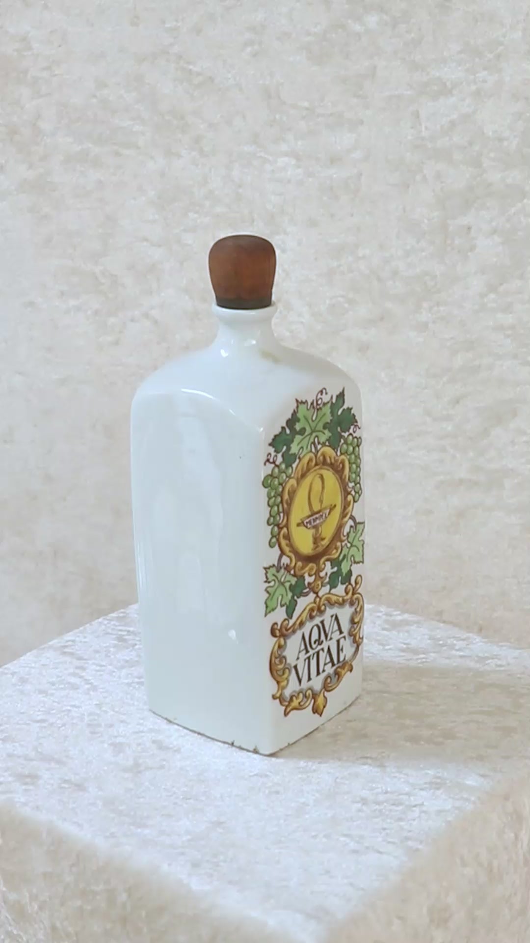 Vintage collectible Hollóházi porcelain bottle specially designed for "Aqua Vitae," which is an old Latin term for "water of life" typically referring to early distilled spirits. Medimpex, who’s name is on a medallion framed with scrolls was a well-known Hungarian/Eastern European pharmaceutical and medical distribution company. The bottle features a green and gold grapevine motifs framing a cartouche with the words "AQVA VITAE" boldly painted in the center. The wooden stopper is in perfect condition. Holló