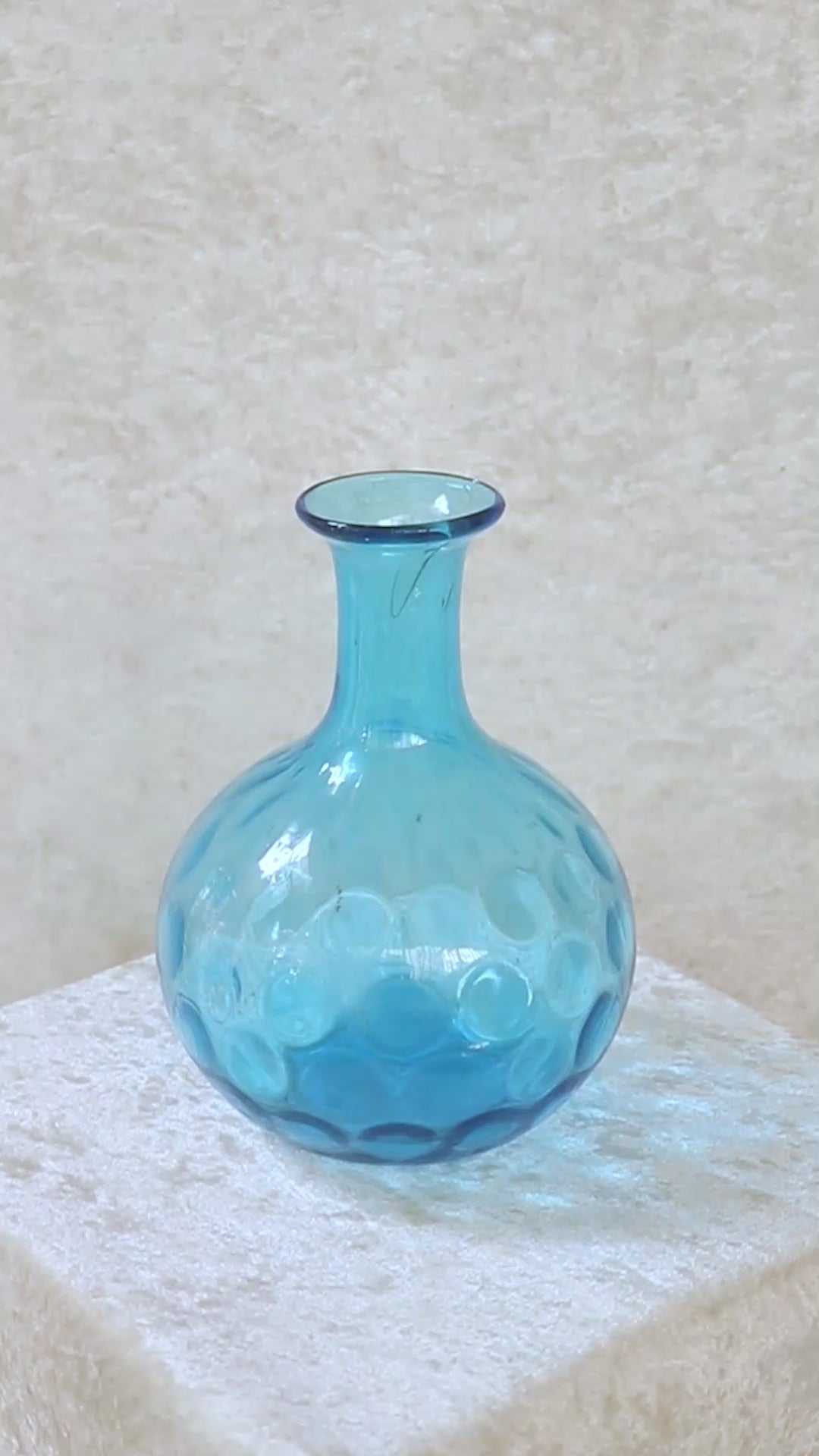 Vintage turquoise blue dimpled glass vase with a onion shaped body. It has a narrow elongated neck which widens out slightly to a rounded rim. The coin, dot or thumbprint pattern on its body is typical of the early to mid 1900s. Can also be used as a decanter.
