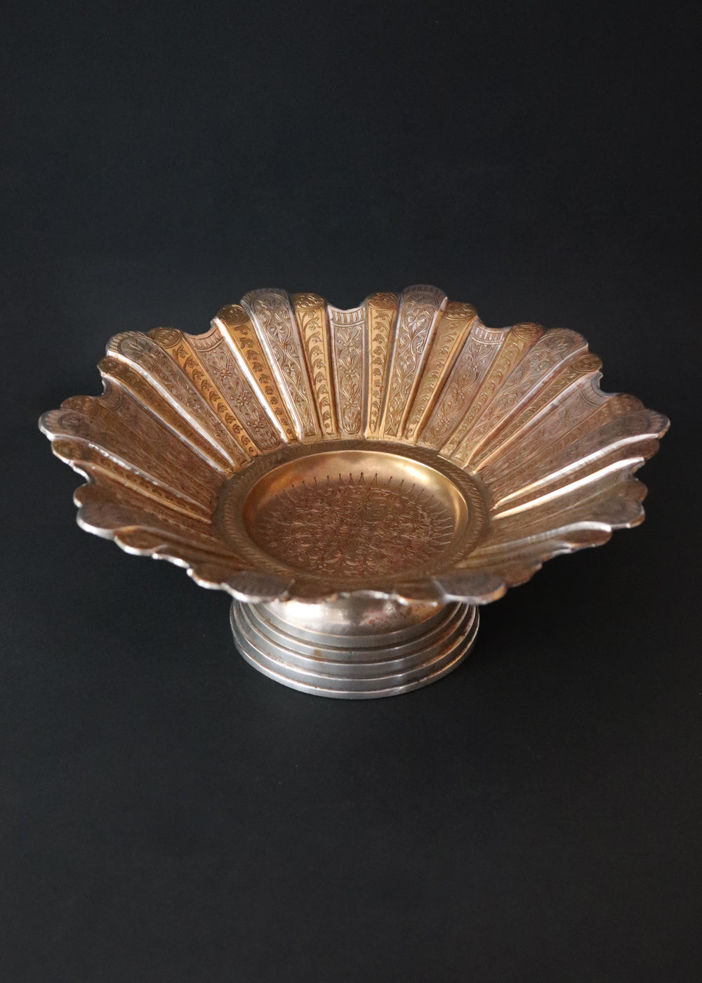 Gorgeous vintage Persian style two-toned fruit bowl in brass. The flower shaped bowl has a scalloped edge and has been constructed with 40 lobed panels at different heights, with alternating gold and silver plating. It is intricately hand-etched throughout. It stands raised on a stepped round base. It would make a beautiful centrepiece for any table. Early to mid 1900s.